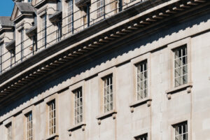 EIFA The curved facade of the historic stone building, reminiscent of a treasure hunt for architectural enthusiasts, boasts multiple windows with ornate details. This majestic structure stands proudly under the clear blue sky, much like a masterpiece at the National Gallery.