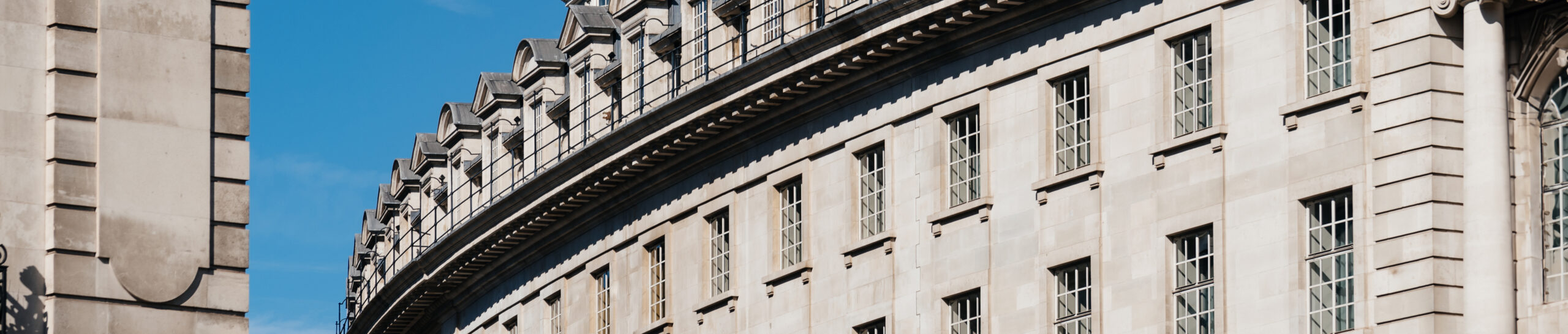 EIFA The curved facade of the historic stone building, reminiscent of a treasure hunt for architectural enthusiasts, boasts multiple windows with ornate details. This majestic structure stands proudly under the clear blue sky, much like a masterpiece at the National Gallery.